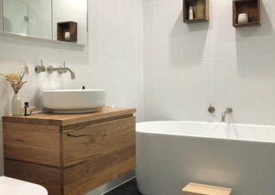 Bathroom with timber vanity, vessel basin, freestanding bath and black floor tiles