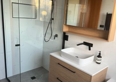 Bathroom with black-framed shower screen, timber vanity and rectangular basin