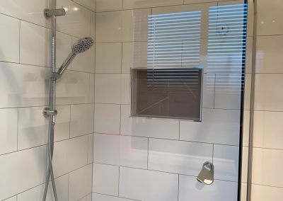 Shower with rail shower, round rain head, recessed niche and white subway tiles