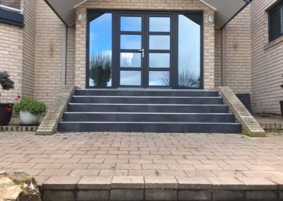 Dark tiled front steps under the gabled entry porch of a brick house