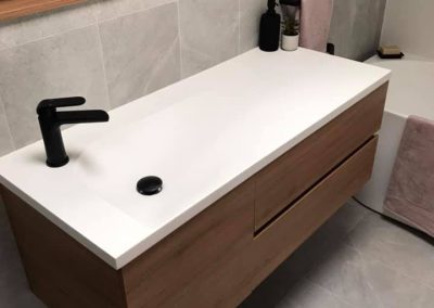 Wall-hung timber vanity with white basin top, black mixer and timber shelf above