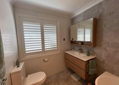 Bathroom with plantation shutters, timber vanity, mirror cabinet and toilet