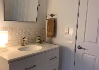 White vanity with undermount basin, arched mirror and mosaic splashback