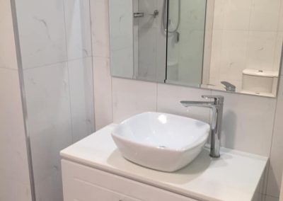 White wall-hung vanity with a vessel basin and mirror cabinet