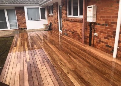 Wide view of a newly oiled timber deck along a red brick house