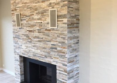 Floor-to-ceiling stacked stone fireplace with a speaker on each side