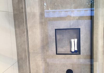 Shower with black rain shower head, black mixer and a black-edged recessed niche