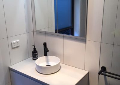 White wall-hung vanity with round vessel basin, black tapware and mirror