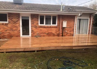 New timber deck across the back of a brick house, wide view