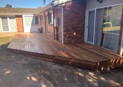 Timber deck along a brick house with sliding glass doors, side view