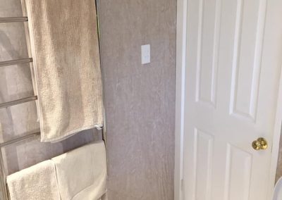 Chrome heated towel ladder with towels beside a white door
