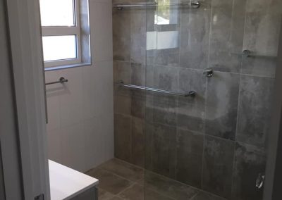 Walk-in shower with frameless glass and dark grey wall and floor tiles
