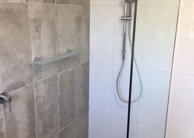 Frameless shower with rail shower and rain head, grey and white wall tiles