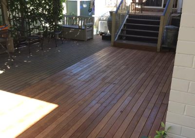 Timber deck with steps up to a back door, shaded by a tree