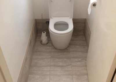 Toilet in a narrow room with marble-look floor tiles