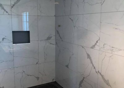 Marble-look wall tiles with a recessed niche during a bathroom renovation