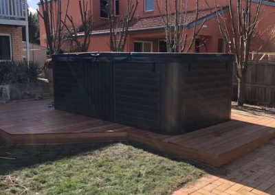 Spa on a timber deck beside lawn and a brick-paved path