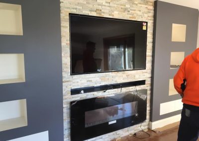 Stacked stone feature wall with a wall-mounted TV and electric fireplace