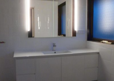 White wall-hung vanity with mirror and wall lights above black and white patterned floor tiles