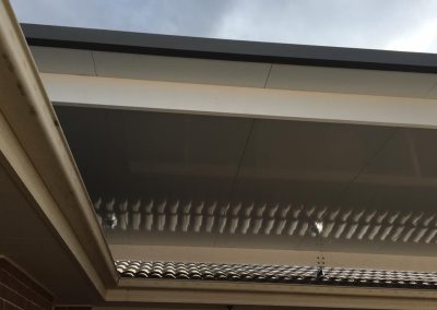 Pergola roof joined to the eaves of a brick house, viewed from below