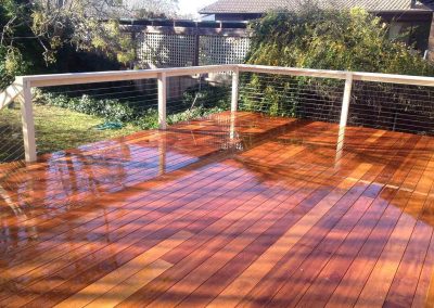 Freshly oiled timber deck with white posts and wire balustrade