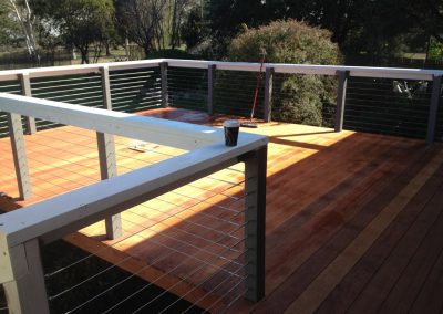 Timber deck with white posts and wire balustrade in the sun
