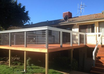 Raised timber deck on posts with wire balustrade and stairs to the garden