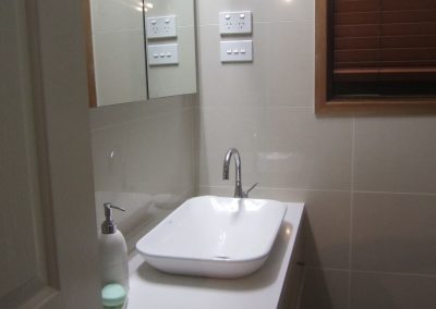 Rectangular vessel basin on a white vanity beside a mirror cabinet