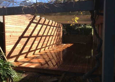 Timber deck under a dark pergola with slatted timber walls