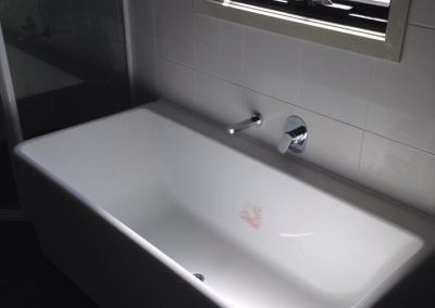 Freestanding bath with wall-mounted tap under a frosted window