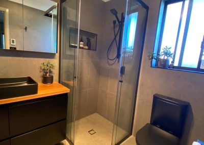 Bathroom with black-framed shower, black vanity with timber top and black toilet