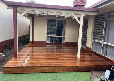 Freshly oiled timber deck under a pergola with artificial turf, wider view