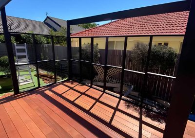 Timber deck with a black steel-framed pergola and balustrade