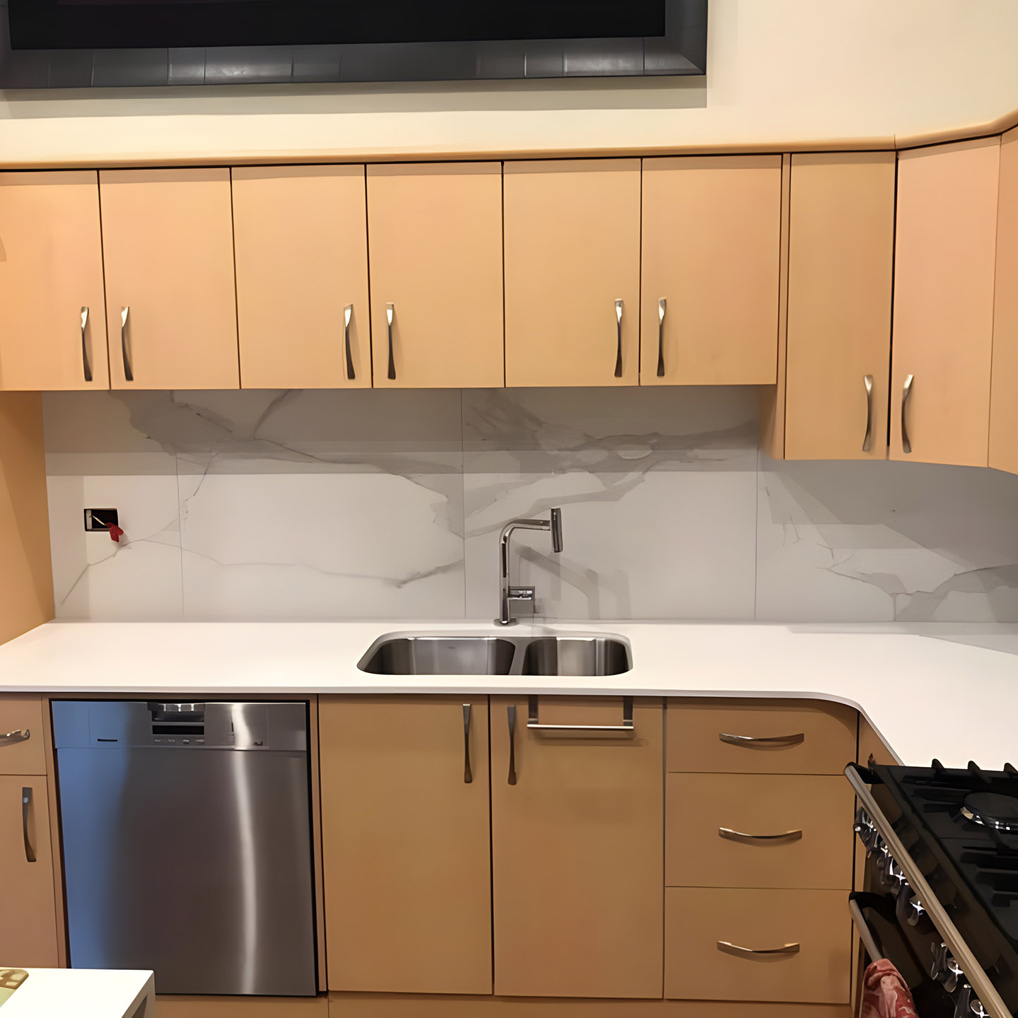 Kitchen with timber-look cupboards, white stone benchtop and marble-look splashback