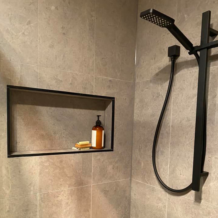 Shower with large grey wall tiles, recessed niche and black rail shower