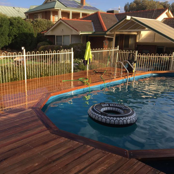 Timber deck built around an above-ground swimming pool with pool fencing