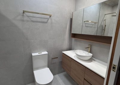 Ensuite with wall-hung timber vanity, vessel basin and brushed brass tapware