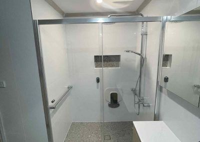 Wide shower with sliding glass doors, grab rail and recessed niche