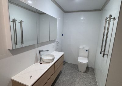 Ensuite with long timber vanity, round vessel basin and speckled floor tiles