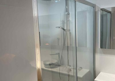 Framed sliding glass shower screen beside a timber vanity