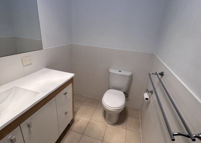 White vanity, toilet and chrome towel rails in a bathroom with beige floor tiles