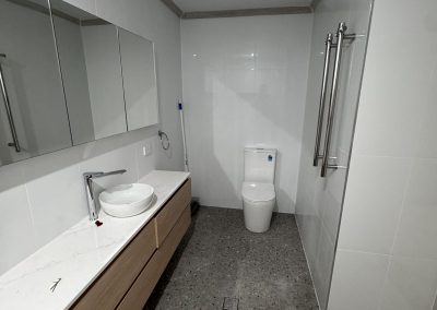 Finished ensuite with long timber vanity, chrome towel rails and speckled floor tiles