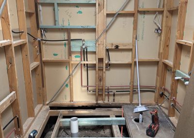 Gutted bathroom with exposed wall frame, new pipework and open floor joists