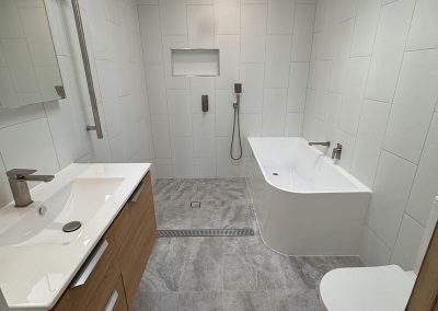 Finished bathroom with timber vanity, bath in a walk-in shower area and skylight