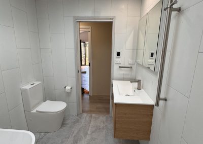 Finished bathroom with toilet, wall-hung timber vanity, heated towel rail and skylight