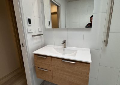 Wall-hung timber vanity with white basin top, mirror cabinet and vertical towel rail