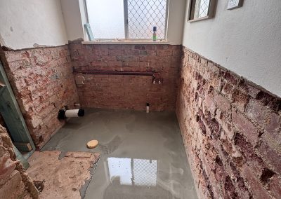 Freshly laid floor screed in a bathroom stripped back to brick walls