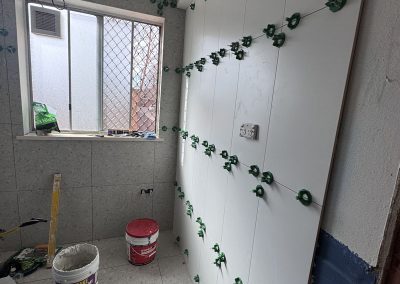 Large white wall tiles going up with green levelling clips