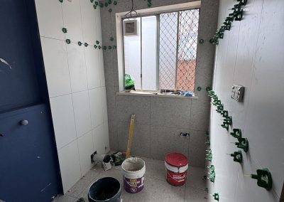 Wall tiling under way with levelling clips, buckets on the floor