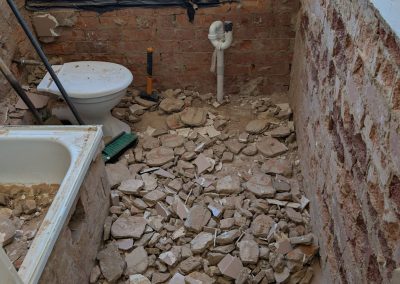 Bathroom floor covered in broken tile rubble during demolition